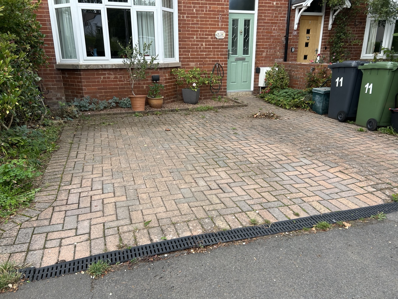 Block paving before cleaning, with weeds and dirt between the joints