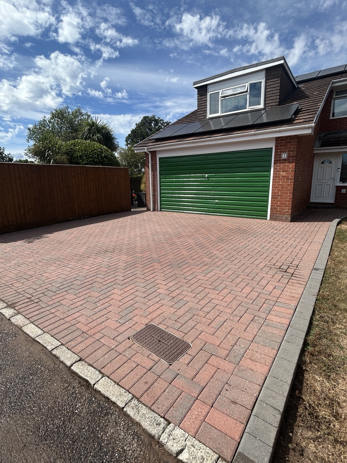 Finished block paving driveway with a green garage door, cleaned by Exe Exteriors