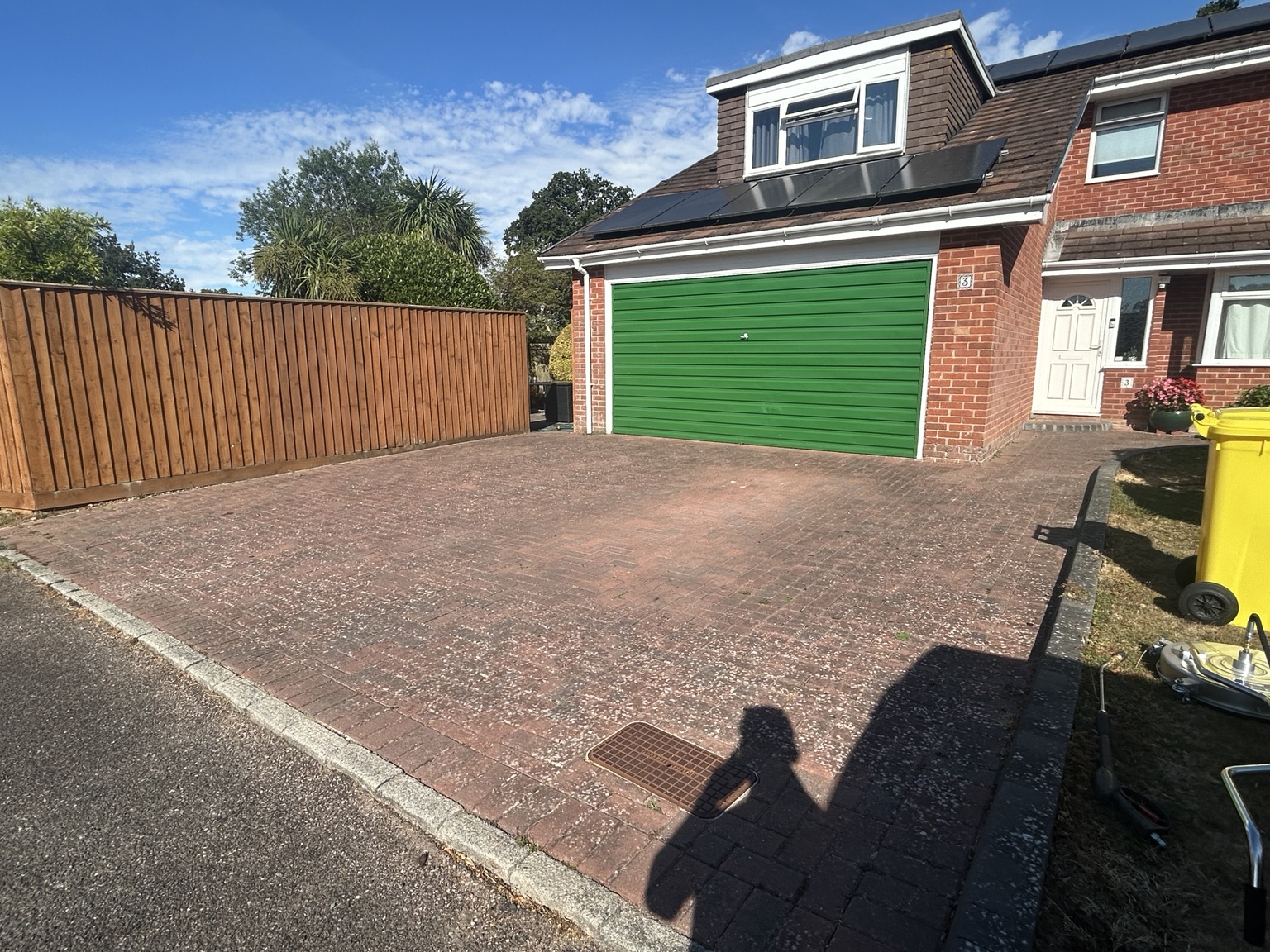 Green-garage block paving driveway before cleaning, with widespread pale surface growth